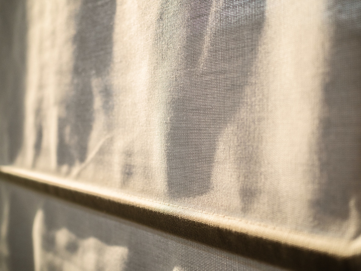 The Roman curtains close a window from the sunset sun. Warm lighting gets through a window