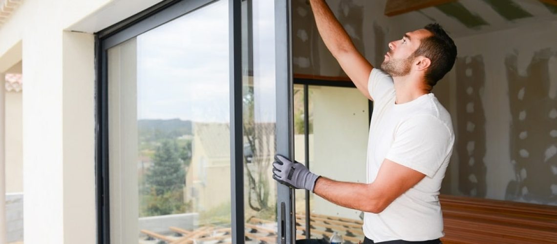 handsome young man installing bay window in a new house construction site